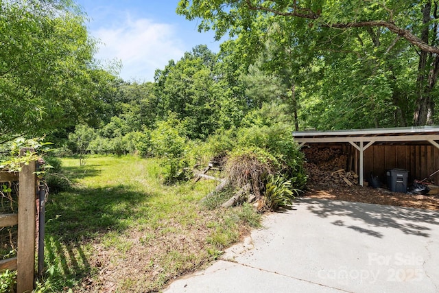 view of yard featuring a carport and a wooded view
