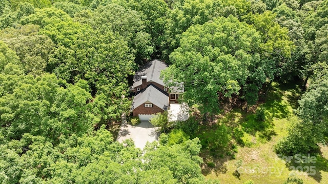 aerial view of property and surrounding area featuring a heavily wooded area