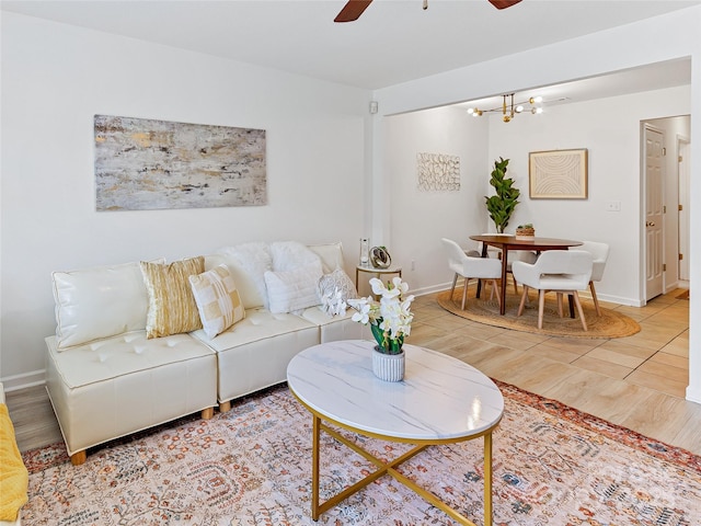 living room with wood finished floors, baseboards, and ceiling fan with notable chandelier