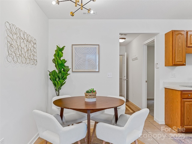 dining space with light tile patterned floors, visible vents, a chandelier, and baseboards