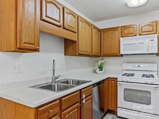 kitchen featuring brown cabinets, a sink, light countertops, tile patterned floors, and white appliances