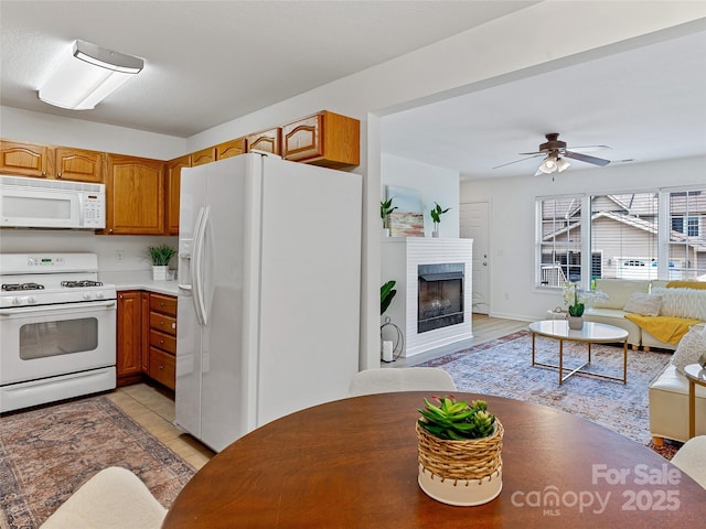 kitchen with brown cabinetry, white appliances, open floor plan, and a brick fireplace