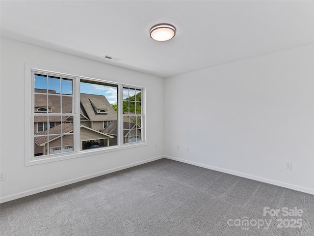 spare room featuring baseboards, visible vents, and dark colored carpet