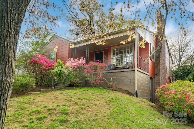 exterior space with covered porch, a front lawn, and a chimney
