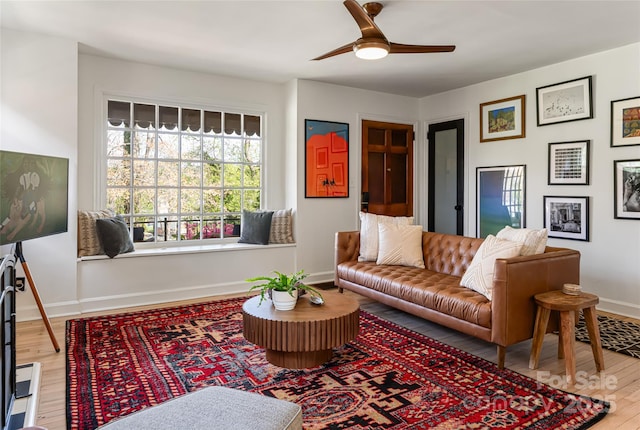 living room featuring baseboards, a ceiling fan, and wood finished floors