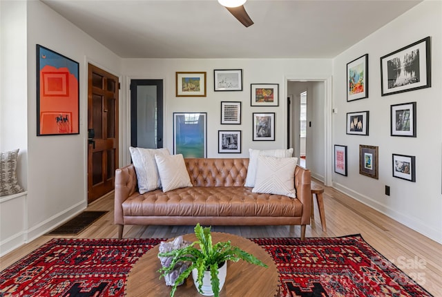 living area featuring baseboards, a ceiling fan, visible vents, and wood finished floors
