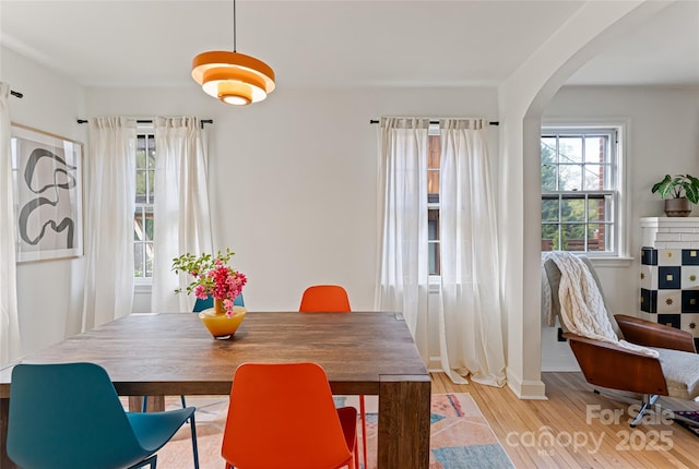 dining area featuring light wood finished floors and arched walkways
