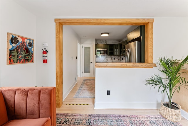 corridor featuring light wood-style flooring and baseboards
