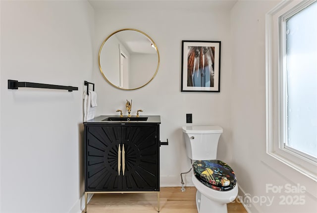 bathroom with baseboards, vanity, toilet, and wood finished floors