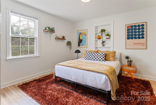 bedroom featuring multiple windows, wood finished floors, and baseboards