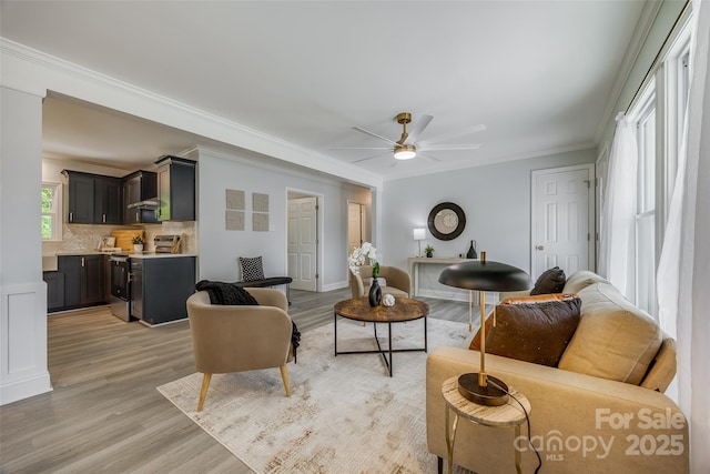 living area featuring light wood-type flooring, ornamental molding, and ceiling fan