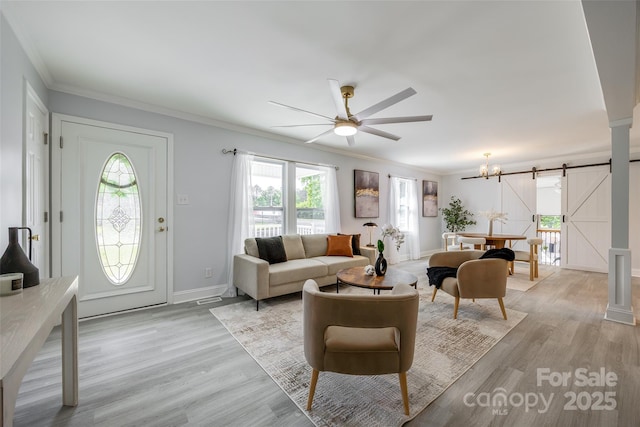 living area featuring a barn door, a healthy amount of sunlight, light wood finished floors, and ceiling fan