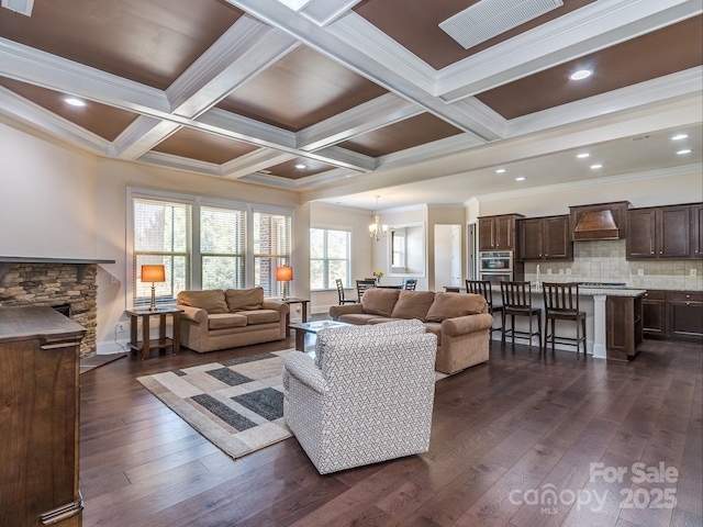 living area featuring dark wood-type flooring, beam ceiling, ornamental molding, and coffered ceiling