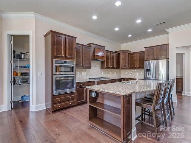 kitchen with visible vents, a sink, baseboards, appliances with stainless steel finishes, and custom exhaust hood