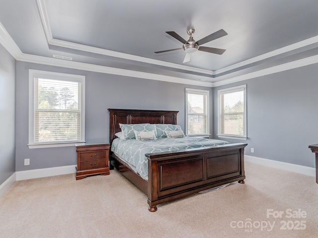 bedroom with a tray ceiling, crown molding, and light carpet