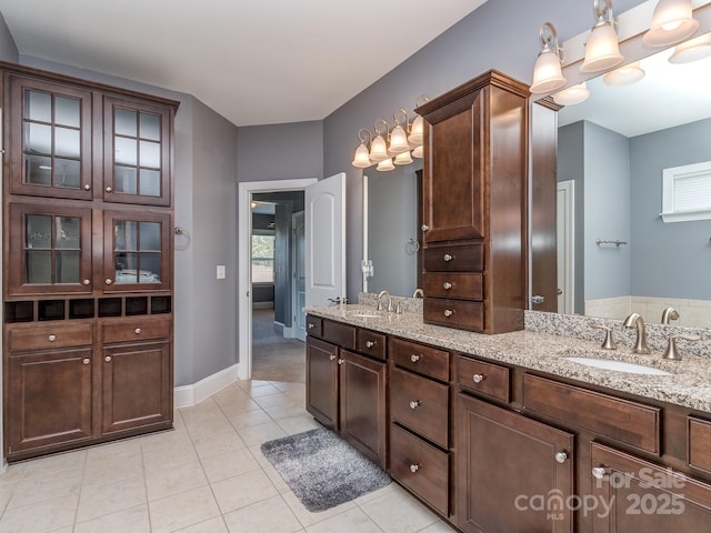 bathroom with baseboards, tile patterned flooring, a sink, and double vanity