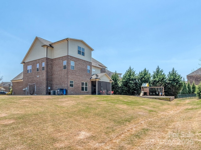 view of side of home featuring central air condition unit, brick siding, a yard, and a playground