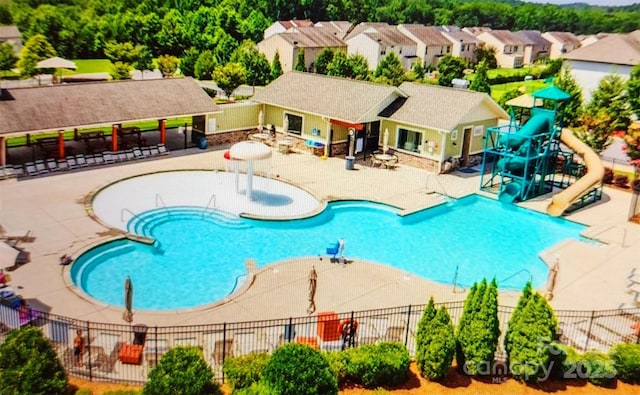 pool featuring a patio area, a water slide, and fence