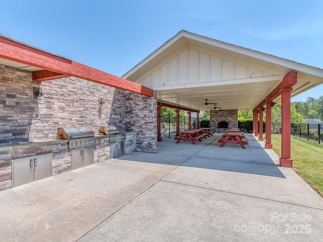 view of patio / terrace featuring an outdoor kitchen, a fireplace, a grill, and fence