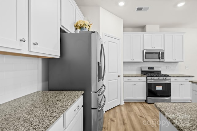 7004 Everly Commons Ln, Tega Cay, SC 29708 - kitchen with white cabinets, decorative backsplash, visible vents, and appliances with stainless steel finishes