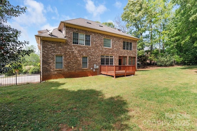 rear view of property with brick siding, a lawn, a wooden deck, and fence