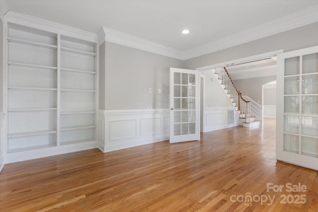 empty room featuring light wood finished floors, french doors, and built in shelves