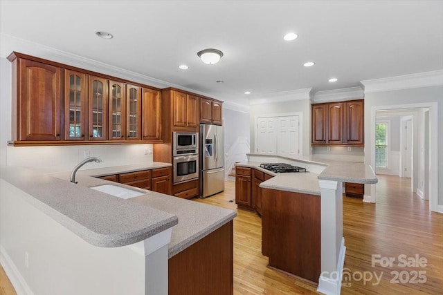 kitchen featuring a kitchen breakfast bar, a sink, crown molding, light countertops, and appliances with stainless steel finishes