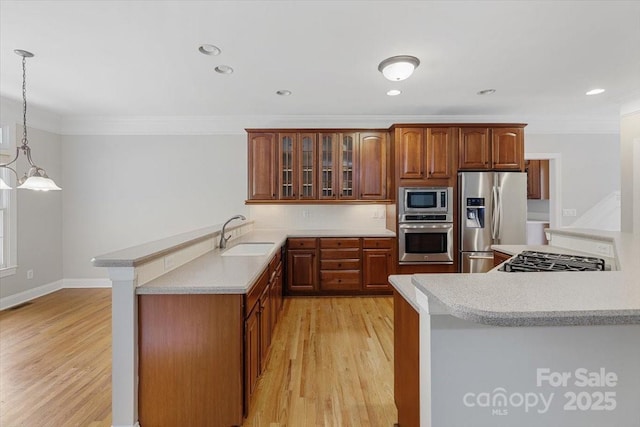 kitchen featuring a peninsula, ornamental molding, a sink, and appliances with stainless steel finishes