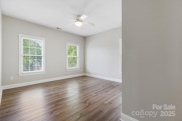 unfurnished room featuring ceiling fan, baseboards, dark wood-style flooring, and visible vents