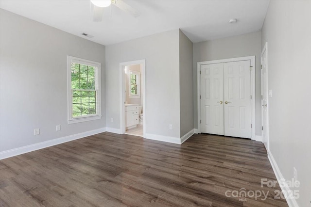 unfurnished bedroom featuring baseboards, visible vents, dark wood-type flooring, and a closet