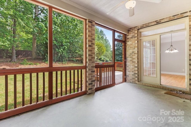 unfurnished sunroom with ceiling fan with notable chandelier