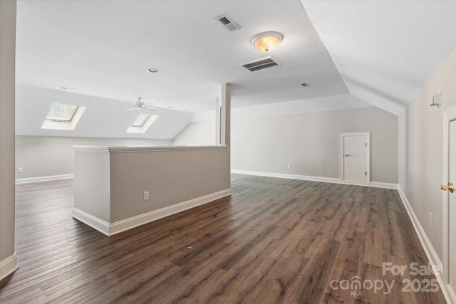 additional living space with vaulted ceiling with skylight, dark wood-type flooring, and visible vents