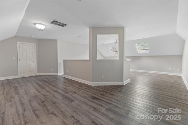 bonus room featuring baseboards, vaulted ceiling with skylight, wood finished floors, and visible vents