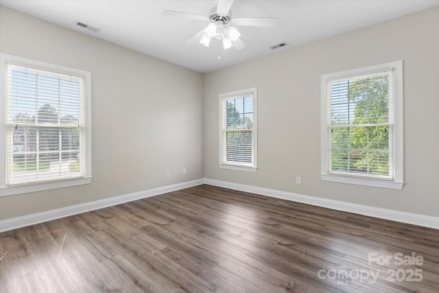 unfurnished room with baseboards, visible vents, ceiling fan, and dark wood-style flooring