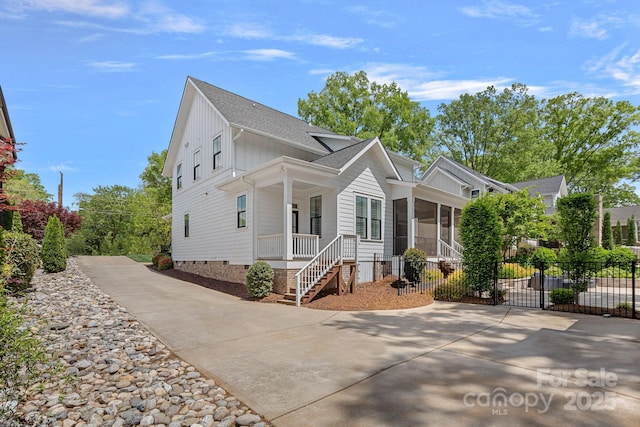 309 Catawba Ave, Davidson, NC 28036 - view of front of house featuring board and batten siding, concrete driveway, crawl space, a sunroom, and a porch