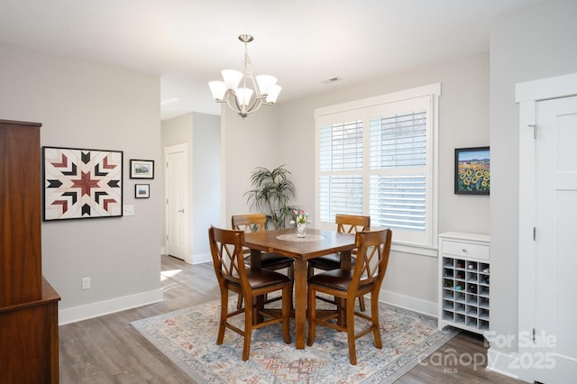 dining space with an inviting chandelier, wood finished floors, visible vents, and baseboards