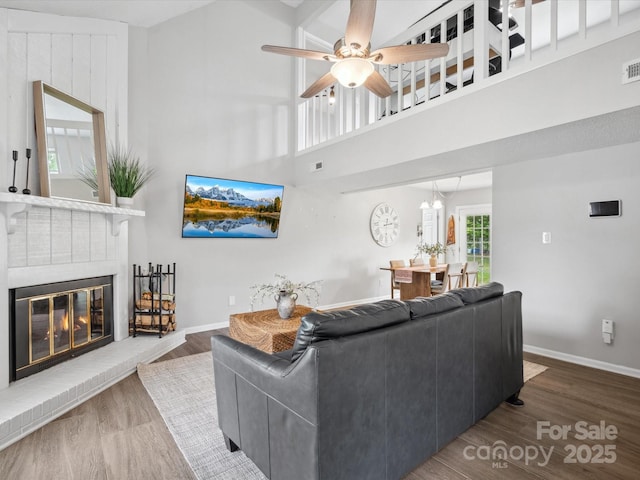 living area featuring a ceiling fan, a brick fireplace, wood finished floors, and visible vents