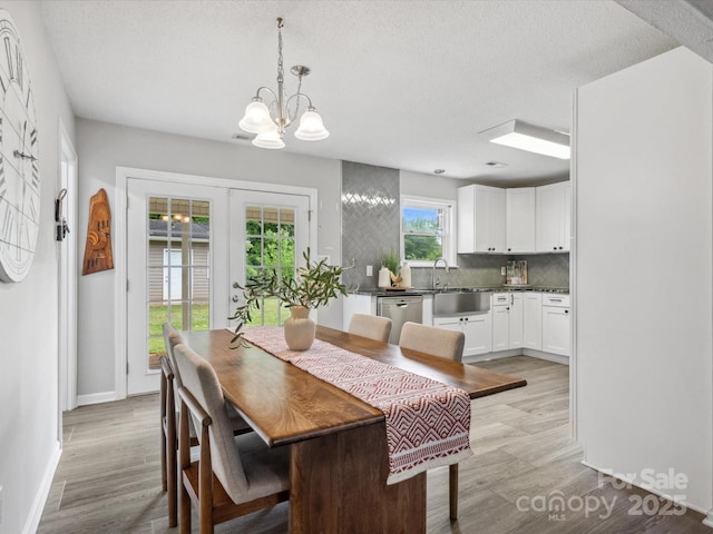 dining room with an inviting chandelier, baseboards, light wood-style floors, and a textured ceiling