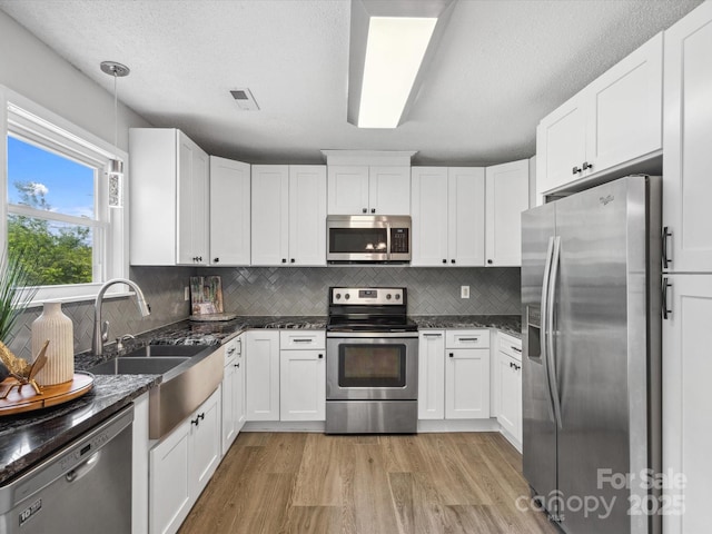 kitchen featuring light wood-style floors, appliances with stainless steel finishes, backsplash, and white cabinets