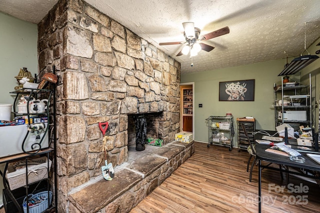 1300 Math Pl, Lenoir, NC 28645 - living room featuring a stone fireplace, a ceiling fan, a textured ceiling, and wood finished floors