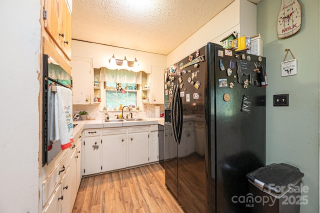 1300 Math Pl, Lenoir, NC 28645 - kitchen featuring wall oven, a sink, light countertops, black refrigerator with ice dispenser, and light wood-style flooring