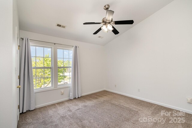 empty room with vaulted ceiling, baseboards, visible vents, ceiling fan, and carpet floors