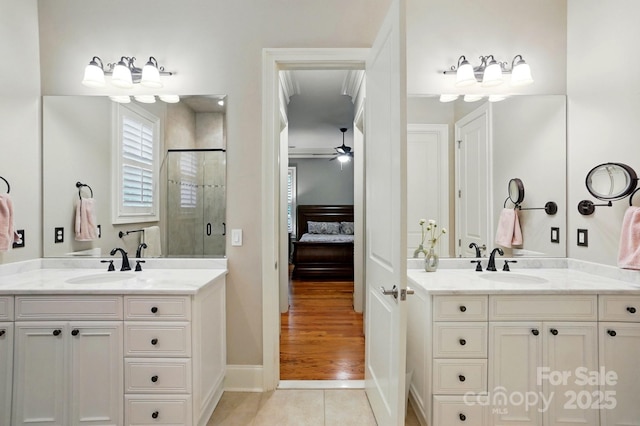 ensuite bathroom featuring a stall shower, connected bathroom, tile patterned flooring, and a sink