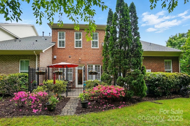 back of property featuring fence, a yard, and brick siding