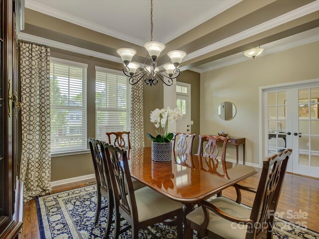 dining room with ornamental molding, wood finished floors, baseboards, a chandelier, and french doors