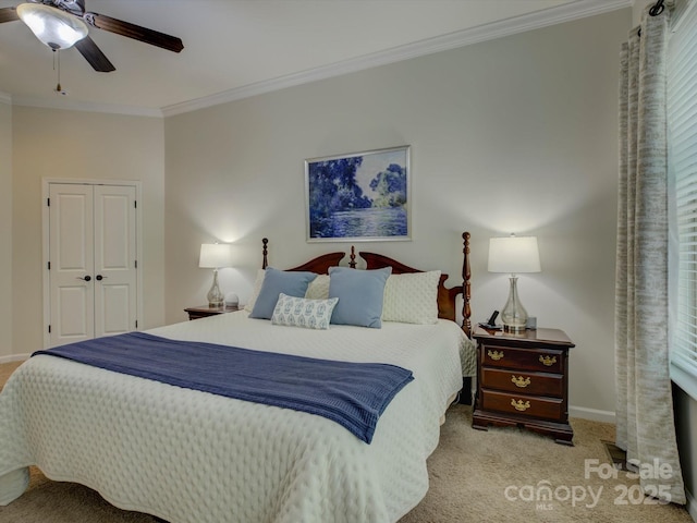 carpeted bedroom with baseboards, ornamental molding, ceiling fan, and a closet