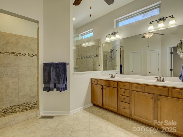 bathroom with double vanity, a walk in shower, ceiling fan, and a sink