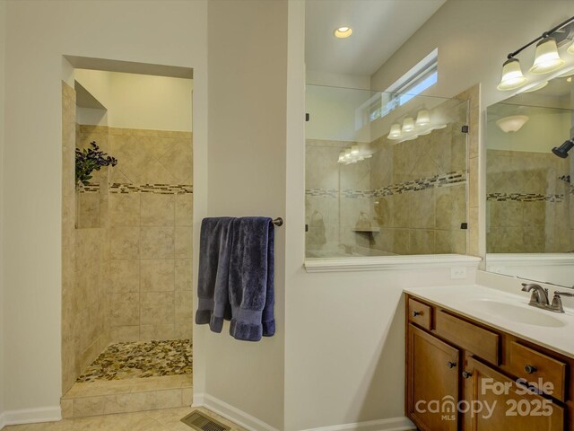 bathroom with vanity, baseboards, walk in shower, and visible vents