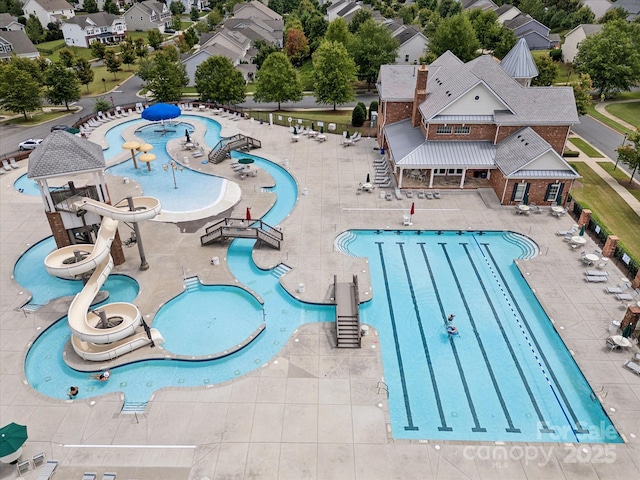 pool with a water play area, a patio area, a water slide, and a residential view