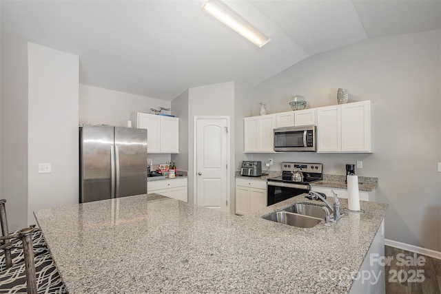 1125 Silvertrace Dr, Salisbury, NC 28144 - kitchen featuring baseboards, white cabinets, a sink, appliances with stainless steel finishes, and vaulted ceiling